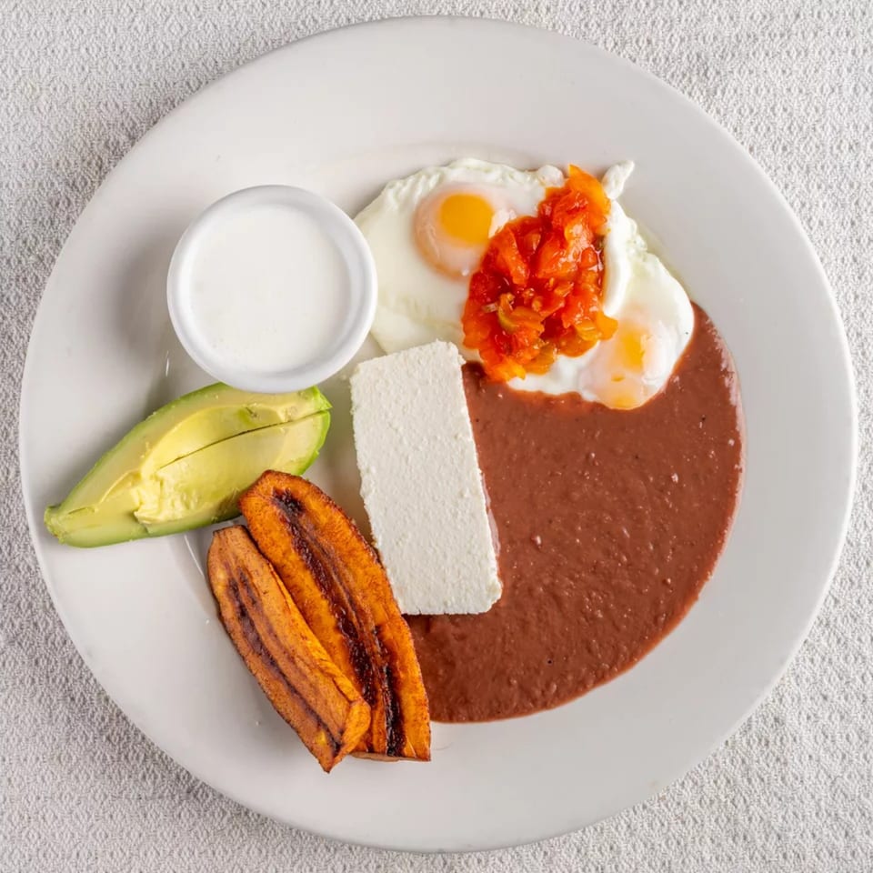 A Montecristo Taqueria y Pupuseria breakfast plate with eggs, beans, cheese, avocado, and plantains.