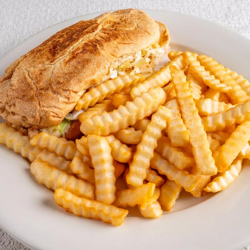 A Montecristo Taqueria y Pupuseria sandwich with shredded cabbage and fries on a white plate.
