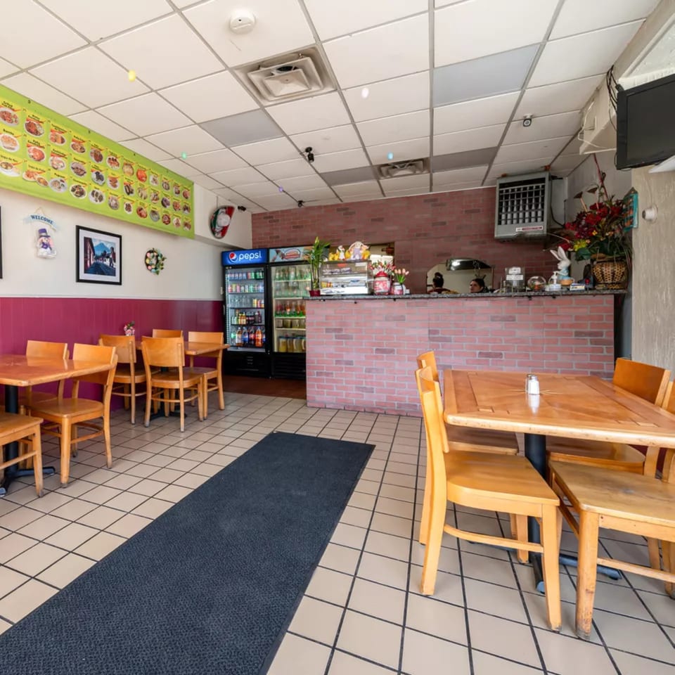 Interior of Montecristo Taqueria y Pupuseria with wooden tables, chairs, and a brick counter.